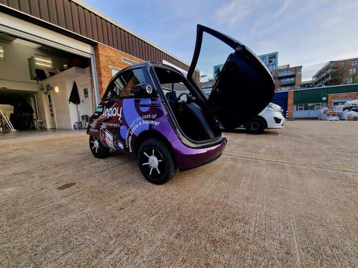 An image of the back left corner of the Lopay car showing the vehicle graphics and wraps with the trunk open